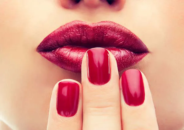 Femme qui embrasse ses ongles rouge